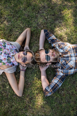 Young couple lying on grass smiling at camera