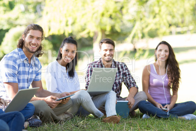 Smiling friends using media devices in park