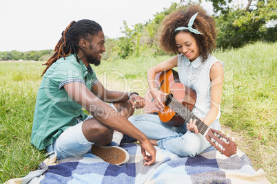 Young couple on a picnic playing guitar