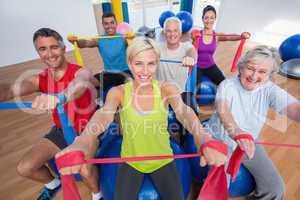 Happy people exercising with resistance bands in gym class