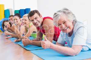 People gesturing thumbs up while lying on mats at gym