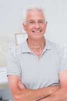 Senior man standing arms crossed in clinic