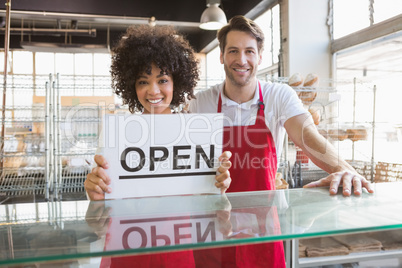 Smiling co-workers showing open sign