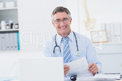 Male doctor holding document at table