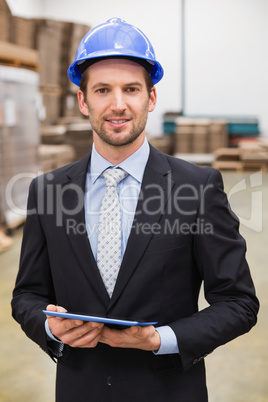 Warehouse manager wearing hard hat using tablet