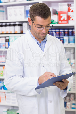 Focused pharmacist writing on clipboard