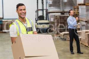 Smiling warehouse worker moving boxes on trolley