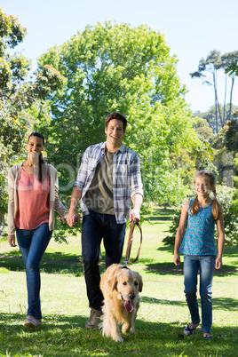 Happy family walking their dog in the park