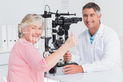 Senior patient gesturing thumbs up while sitting with optician
