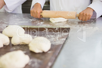 Baker kneading dough with rolling pin