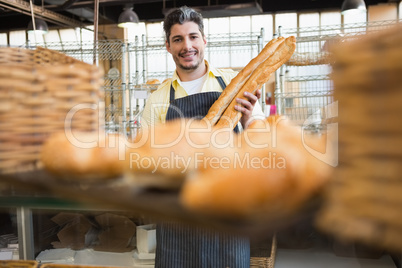 Cheerful waiter holding two baguettes