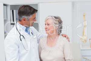 Doctor consoling senior woman in clinic