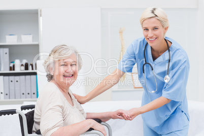 Friendly nurse holding senior patients hand