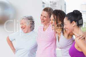 Friends standing arms around in fitness studio