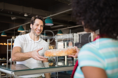 Waitress behind the counter giving loaf to customer
