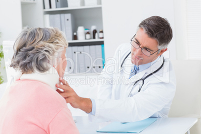 Doctor examining female patient wearing neck brace