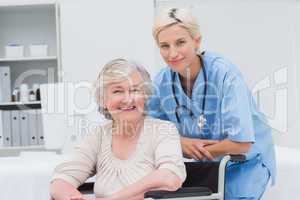 Nurse leaning on senior patients wheelchair at clinic