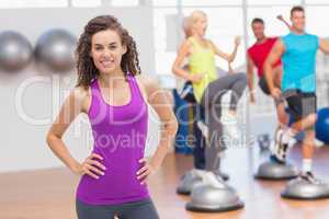 Happy fit woman standing hands on hips at gym