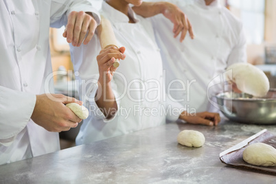 Colleagues holding rolling pin and dough
