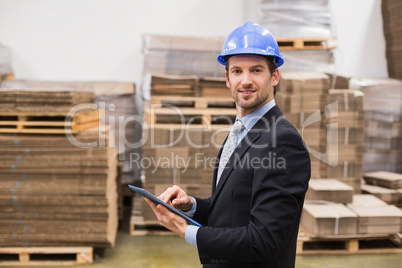 Warehouse manager wearing hard hat using tablet