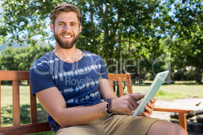 Young man using tablet on park bench