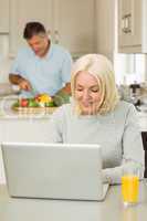 Happy mature blonde using laptop