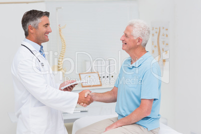 Male doctor and senior patient shaking hands