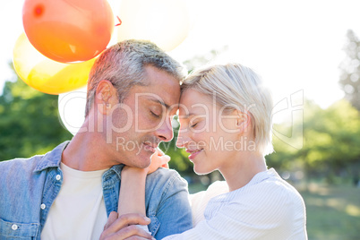 Cute couple holding balloons at the park