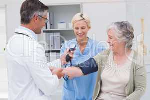 Doctor and nurse checking senior patients blood pressure