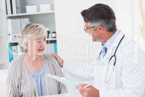 Doctor consoling senior woman in clinic