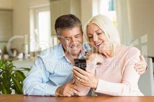 Happy mature couple looking at smartphone together