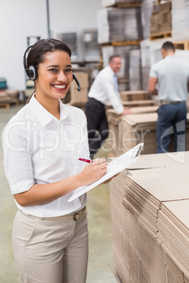 Warehouse manager writing on clipboard