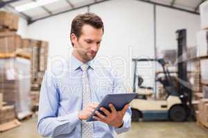 Manager using digital tablet in warehouse