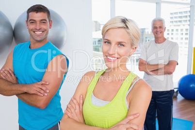 Happy friends standing arms crossed at gym class