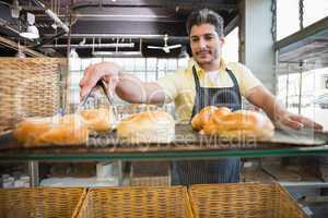 Smiling waiter taking bread with tongs