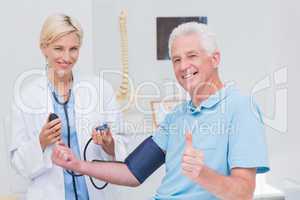 Patient showing thumbs up while doctor checking his blood pressu