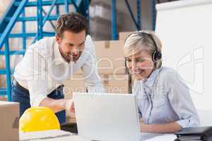 Warehouse managers using laptop and wearing headset