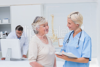 Nurse discussing with patient while doctor using computer