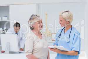 Nurse discussing with patient while doctor using computer