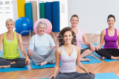 Class practicing yoga with instructor at gym