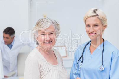 Nurse and senior patient smiling in clinic