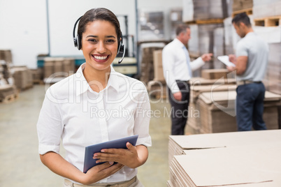 Warehouse manager wearing headset holding clipboard