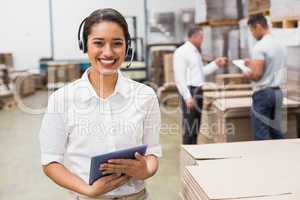 Warehouse manager wearing headset holding clipboard