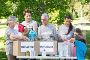 Happy volunteer family separating donations stuffs