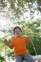 Happy little boy on a swing in the park