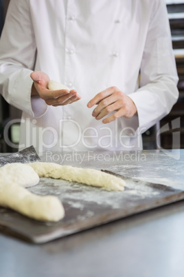 Baker making uncooked dough on tray