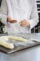 Baker making uncooked dough on tray