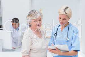 Nurse communicating with patient while doctor using computer
