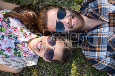 Young couple lying on grass smiling at camera