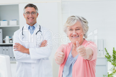 Patient showing thumbs up sign while standing with doctor